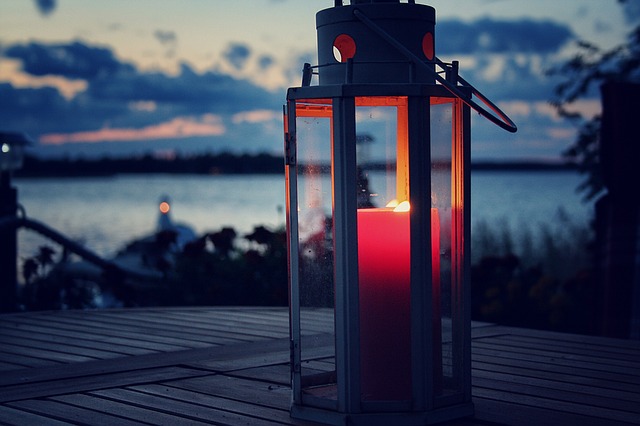 farol rojo con vela y un lago al fondo